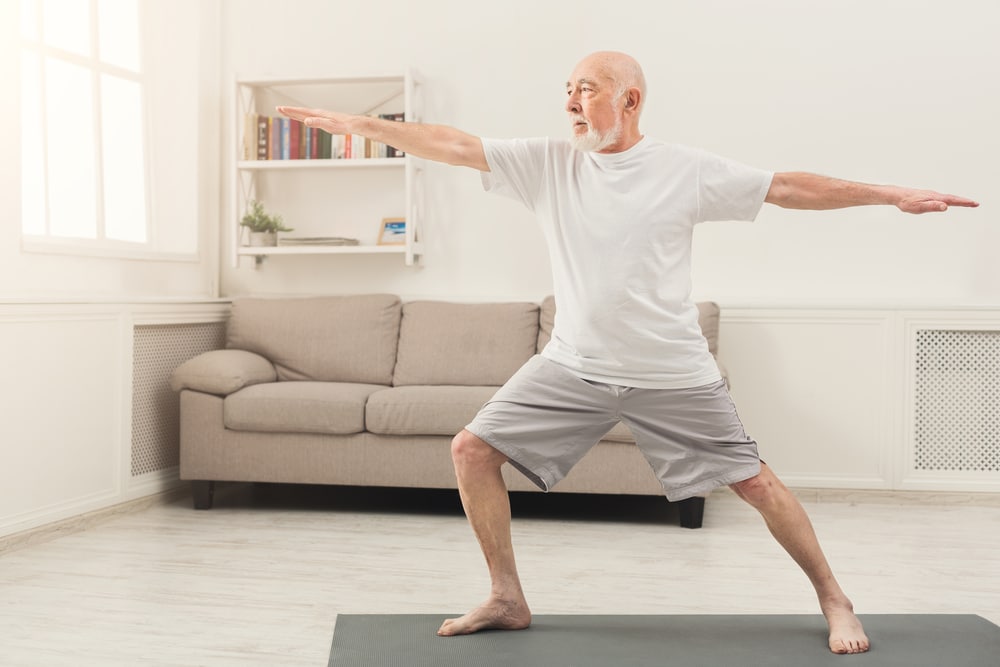 senior man doing yoga indoors
