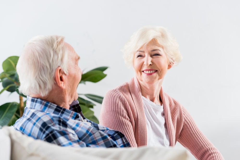 senior couple talking and smiling while seated indoors