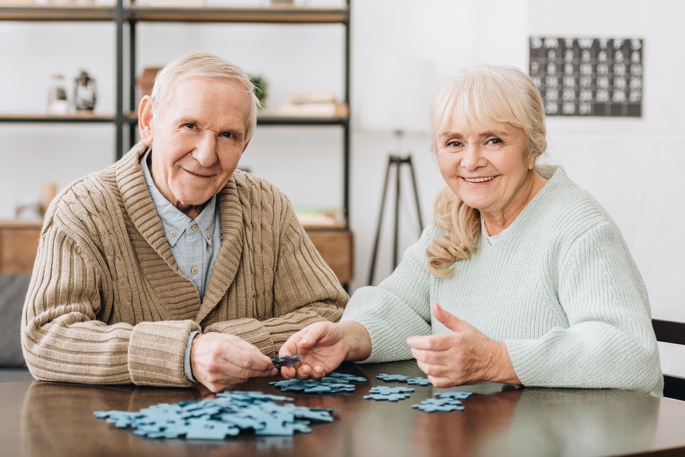 two seniors smiling while doing puzzle