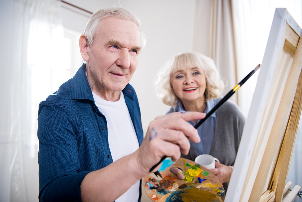 Senior man painting, senior woman smiling