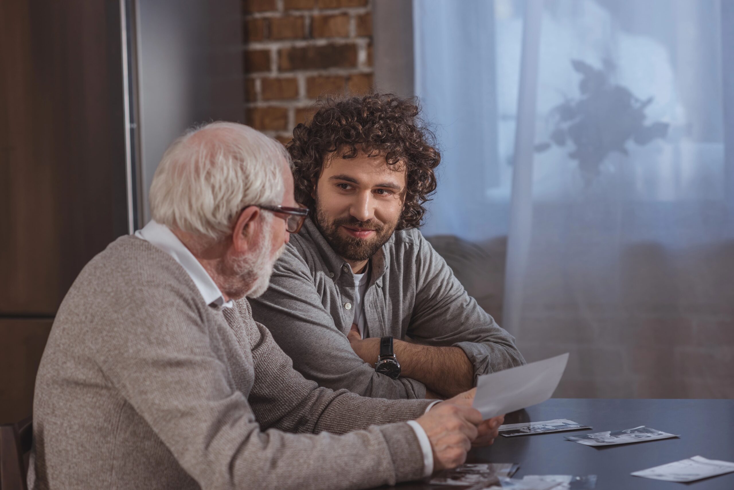 Senior man and young man looking at old photos together